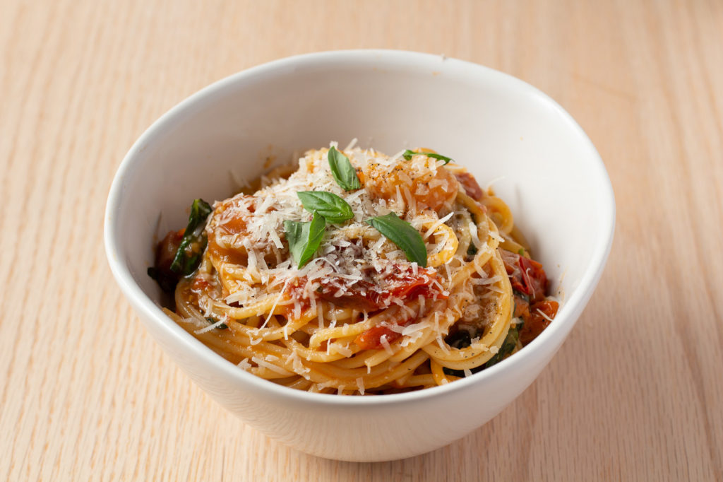 spaghetti in a bowl with cherry tomatoes, pancetta and basil